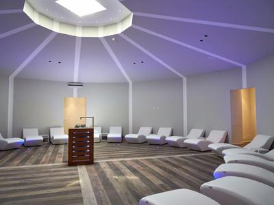 Sala relax circolare per il benessere con sdraio bianche e illuminazione soffusa.