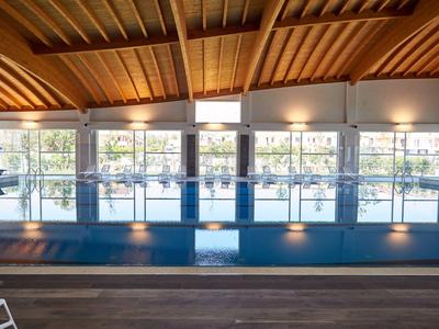Vista interna di una piscina coperta moderna con soffitto in legno e grandi finestre