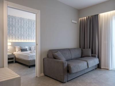 Modern hotel room with sofa bed and adjoining bedroom with double bed.