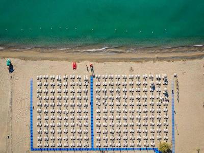 Vista aerea di una spiaggia organizzata con ombrelloni e lettini vicino al mare.