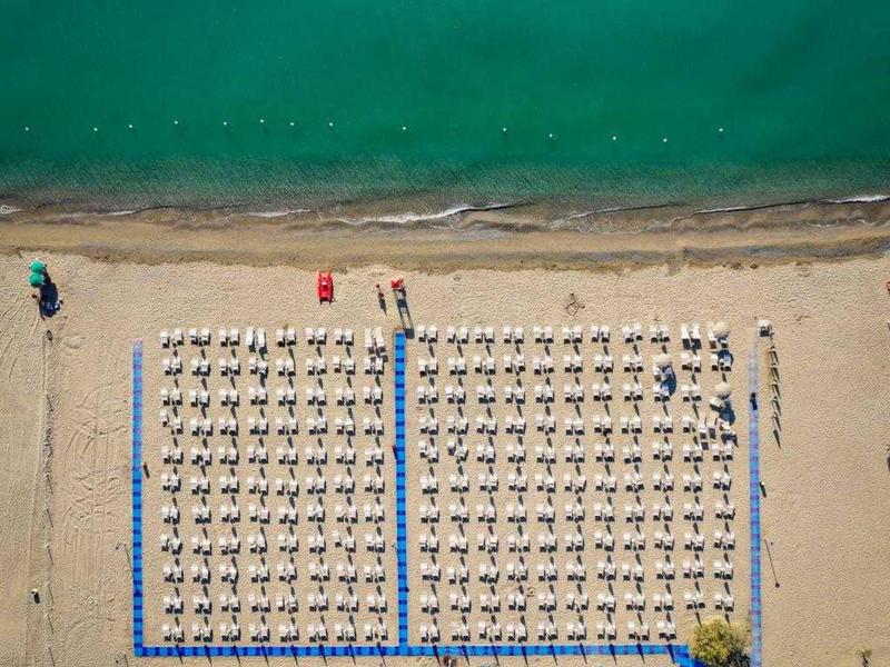 Vista aerea di una spiaggia organizzata con ombrelloni e lettini vicino al mare.