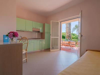 Heller Küchenbereich mit grünen Schränken und Zugang zu einer Terrasse mit Gartenblick.