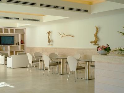 Heller Hotel-Loungebereich mit weißen Stühlen, Tischen und maritimen Wanddekorationen.