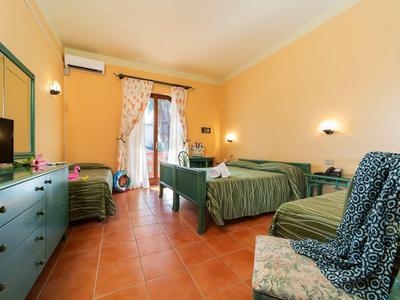 Cozy hotel room with two single beds, TV, chairs, and terrace.