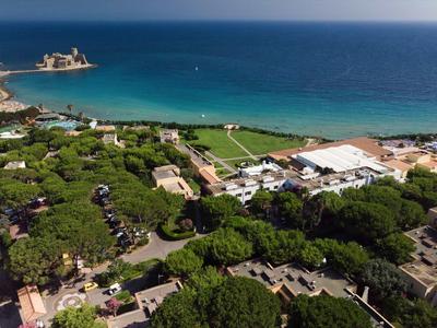Aerial view of a coastal town with clear blue sea and green forested area.