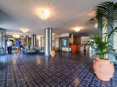 Hotel lobby with blue patterned tiles, large plants, and seating areas.