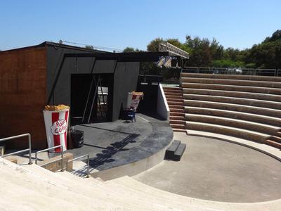 Moderní venkovní amfiteátr s sedadly a reklamními tabulemi za denního světla.