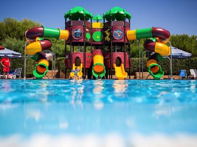 Colorful water playground with slides in a hotel pool under sunny sky.