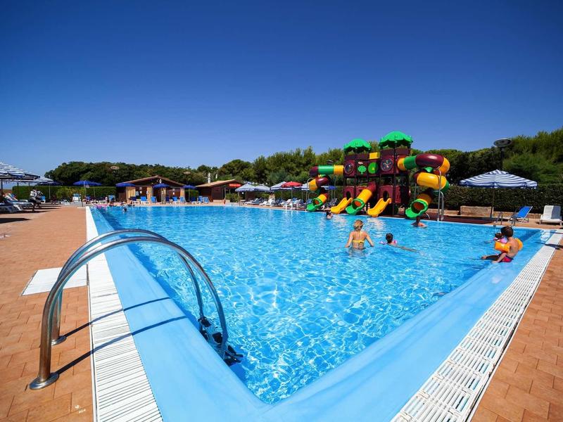 Large outdoor pool with water slides and sun loungers under a blue sky.