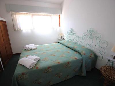 Chambre confortable avec lit, couverture verte, serviettes et fenêtre avec rideaux.