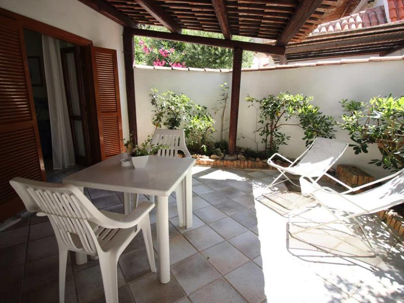 Terrasse confortable avec chaises en plastique blanches et table près du mur de la maison.