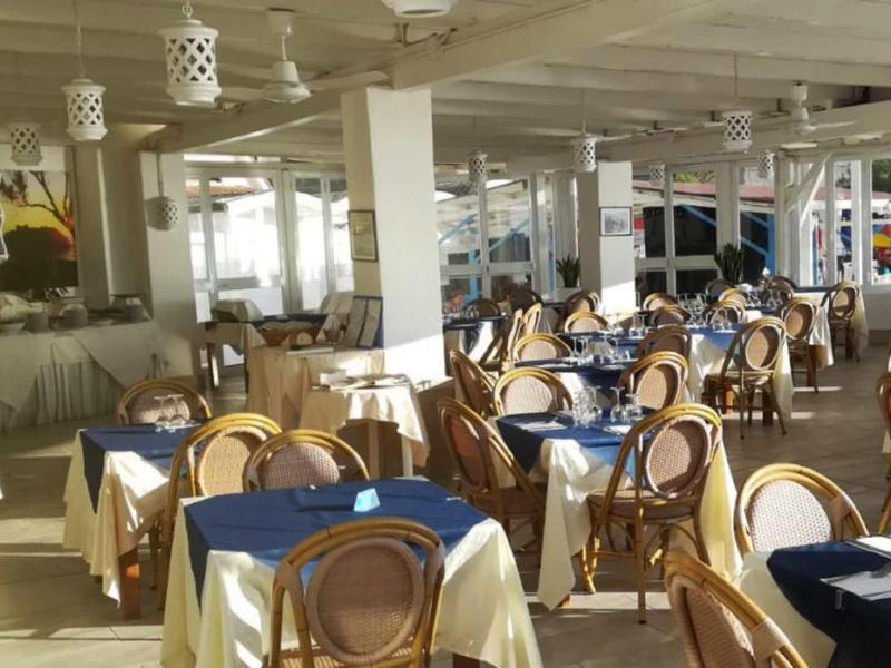 Salle à manger lumineuse avec des tables couvertes de blanc et des chaises en bois dans un hôtel.