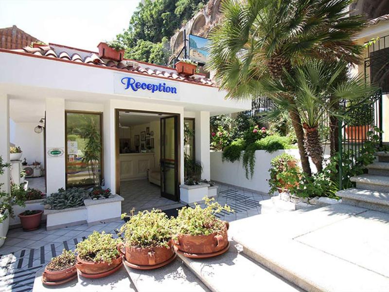 Hall d'hôtel lumineux avec réception, plantes extérieures et escaliers à côté de l'entrée