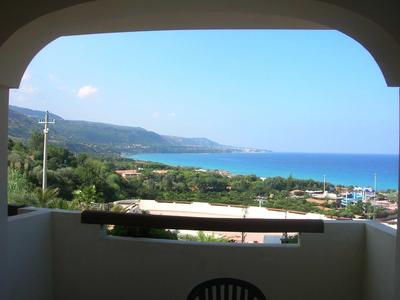 Výhled z kryté terasy na moře, pobřeží a zelenou krajinu