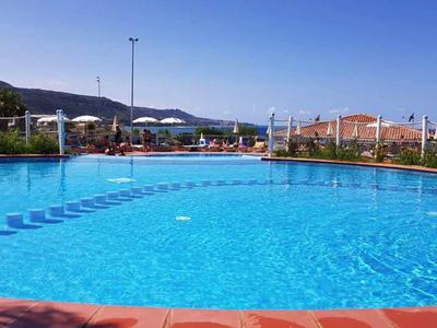 Velký bazén s čistou vodou a slunečníky v rekreačním prostředí