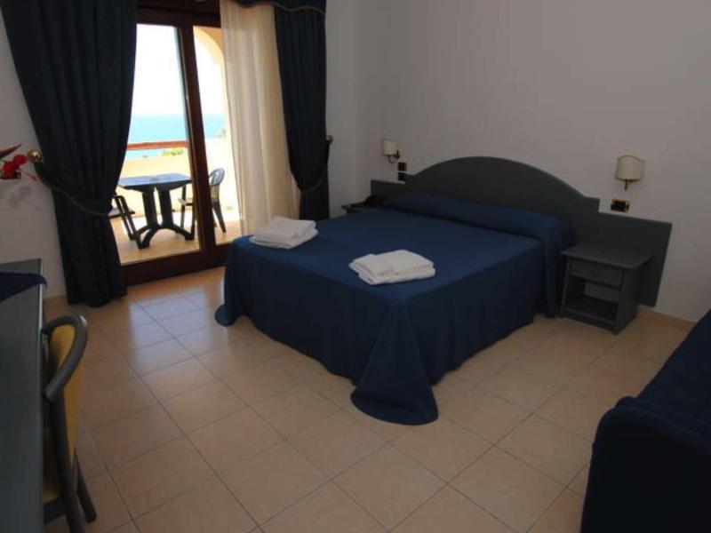 Hotelový pokoj s manželskou postelí, jednolůžkem a balkonem s výhledem na moře.