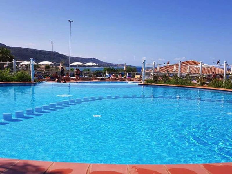 Velký bazén s čistou vodou a slunečníky v rekreačním prostředí