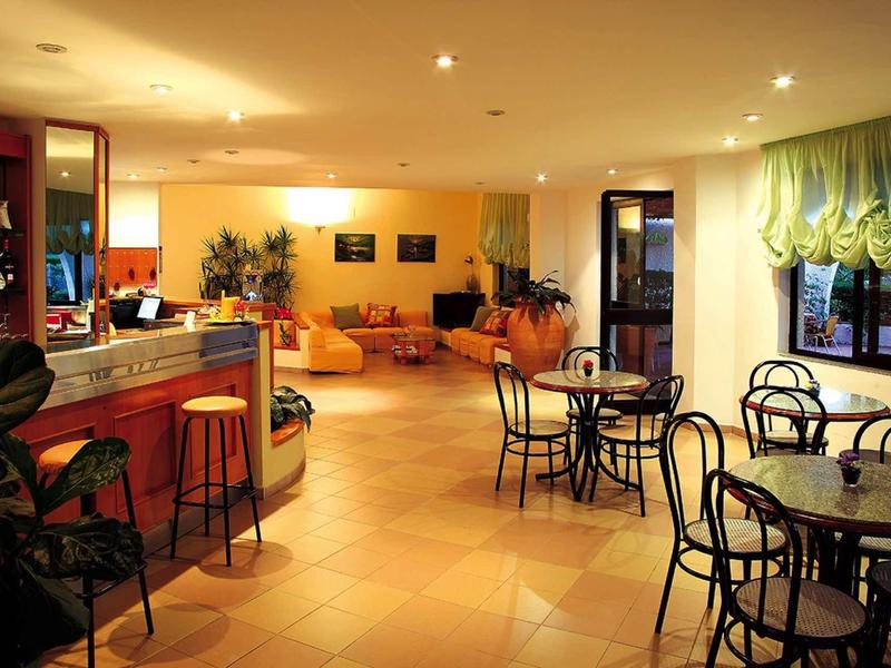 Gemütlicher Caféinnenraum mit Tischen, Stühlen, Tresen und warmer Beleuchtung.