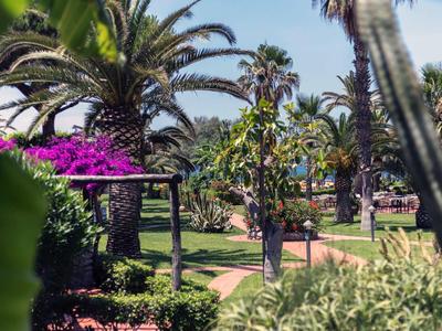 Tropikalny ogród z palmami i kolorowymi kwiatami w słoneczny dzień.