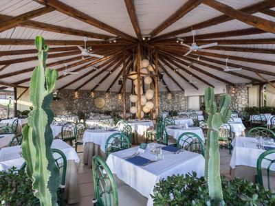 Duża okrągła jadalnia z drewnianym sufitem z belkami i białymi stołami w hotelu.