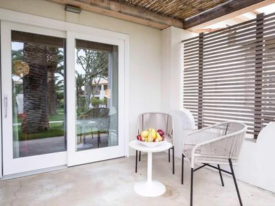 Przytulny taras z białymi krzesłami i małym stolikiem przed szklanymi drzwiami.