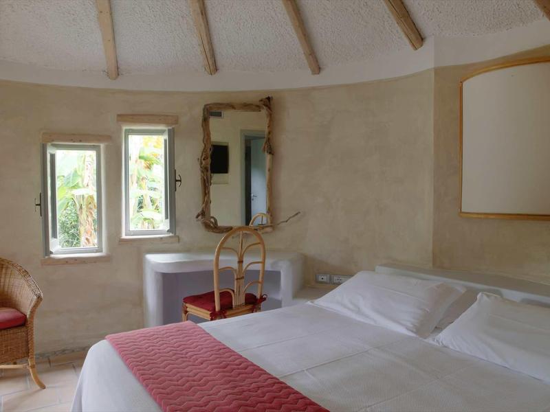 Przytulny pokój hotelowy z łóżkiem podwójnym, dwoma oknami, lustrami i krzesłem.