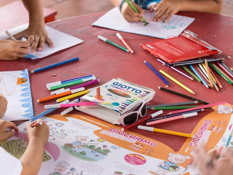 Dzieci rysujące i kolorujące przy stole z kredkami i kolorowankami.