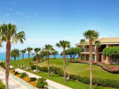 Hotelanlage mit Palmen und Blick auf das Meer unter blauem Himmel.