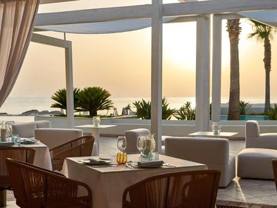 Terrazza con tavoli apparecchiati e vista sul mare al tramonto.