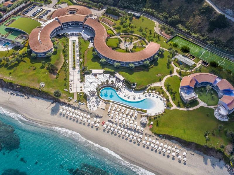 Hotel di lusso con architettura curva, grande piscina e accesso diretto alla spiaggia.