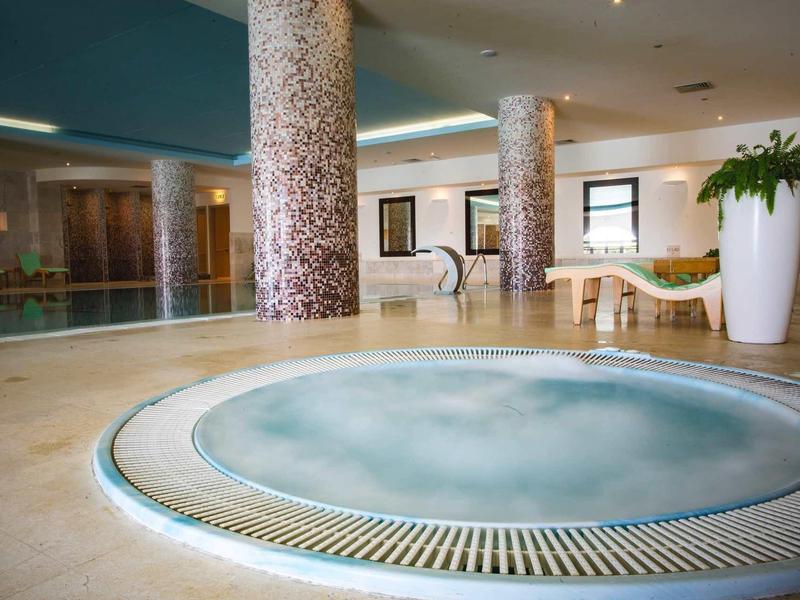 Wnętrze z jacuzzi, leżakami i dekoracyjnymi kolumnami w hotelu.