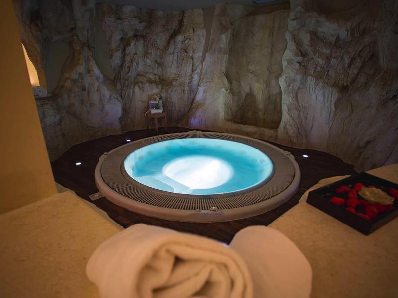 Przytulny jacuzzi w skalnej jaskini z ręcznikiem i płatkami róż.