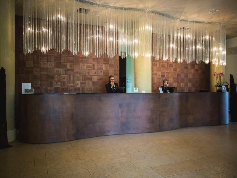 Nowoczesna recepcja hotelowa z dwoma pracownikami za długim ciemnym konturem.