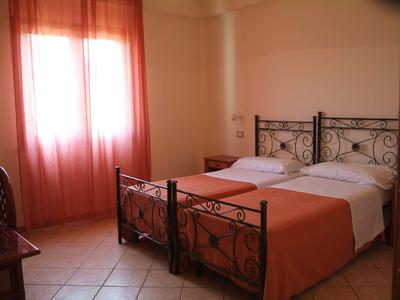 Camera doppia con letti in ferro battuto e tende arancioni.