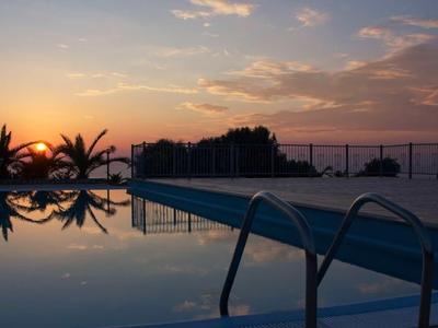 Piscina al tramonto con cielo riflesso e palme