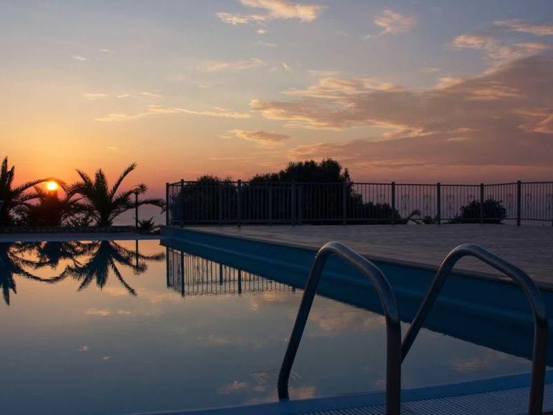 Piscina al tramonto con cielo riflesso e palme