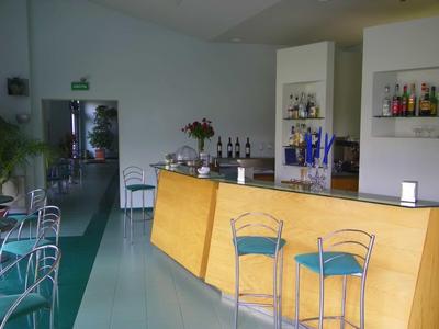 Modern hotel bar area with wooden counter and chairs with blue cushions.