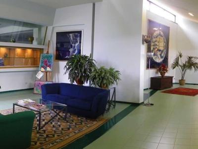 Brightly lit hotel corridor with seating, plants, and modern decor.