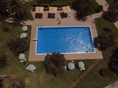 Rectangular pool with lounge chairs and umbrellas on a well-maintained lawn