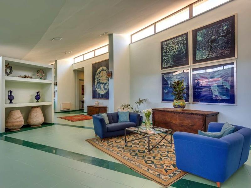 Modern hotel lobby with blue armchairs, wooden sideboard, and decorative wall art.