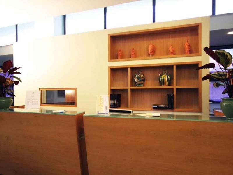 Modernly furnished hotel lobby area with wooden furniture and plants.