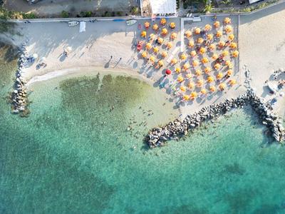 Vista aérea de playa con sombrillas y agua turquesa clara junto a zona hotelera.
