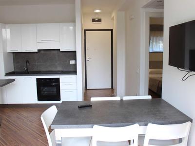 Zona pranzo moderna con cucina bianca e pavimento in legno in uno spazio aperto.