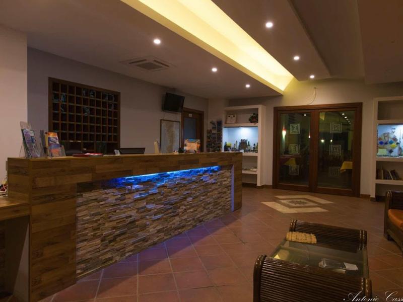 Reception dell'hotel con banco illuminato e area salotto dal design moderno.