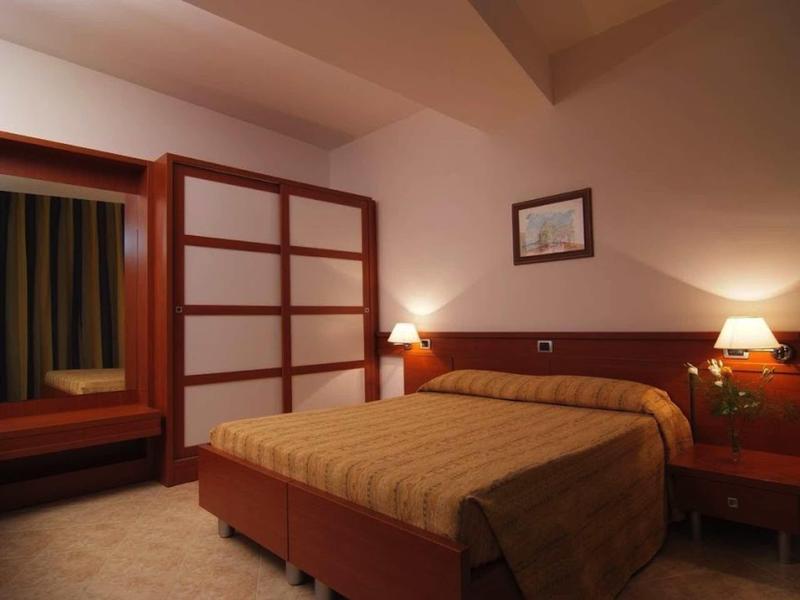 Gemütliches Schlafzimmer mit Doppelbett, Holzschränken, Nachttischen und warmem Licht.