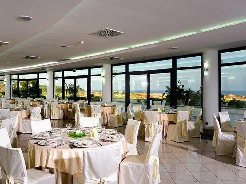 Eleganter Partyraum mit weißen Stühlen, runden Tischen und Panoramafenstern mit Meerblick.