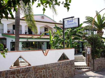 Hôtel avec végétation tropicale et mur en pierre au premier plan, ciel ensoleillé.