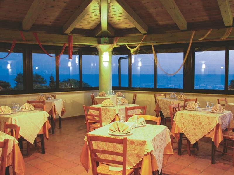 Restaurant chaleureux avec plafond à poutres en bois et tables dressées au crépuscule.