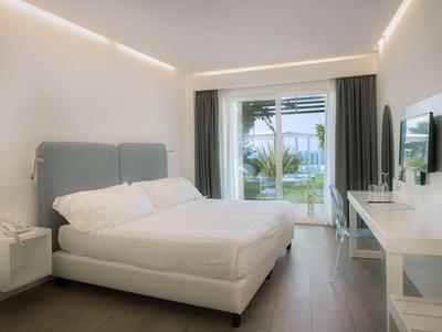 Nowoczesny pokój hotelowy z podwójnym łóżkiem, biurkiem i widokiem na taras z ogrodem.