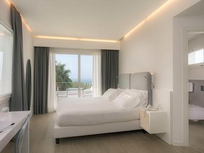 Nowoczesny pokój hotelowy z dużym łóżkiem, oknem z widokiem na morze i przyległą łazienką.